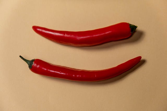 two cayenne peppers on a brown background