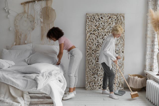 Two women cleaning a bedroom