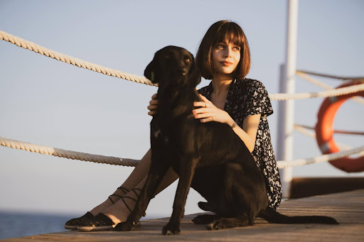 Woman sitting on a boardwalk with a dog